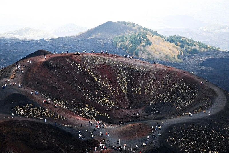 Vulkansk krater med besøgende på mørke askeskråninger ved Etna
